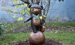 Miś Uszatek w Łodzi, stojąc na kuli ziemskiej z walizką, gotów do podróży.