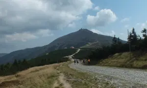 Szlak na Śnieżkę z Szklarskiej Poręby. Grupa turystów wędruje kamienistą ścieżką pod górę, w kierunku szczytu.