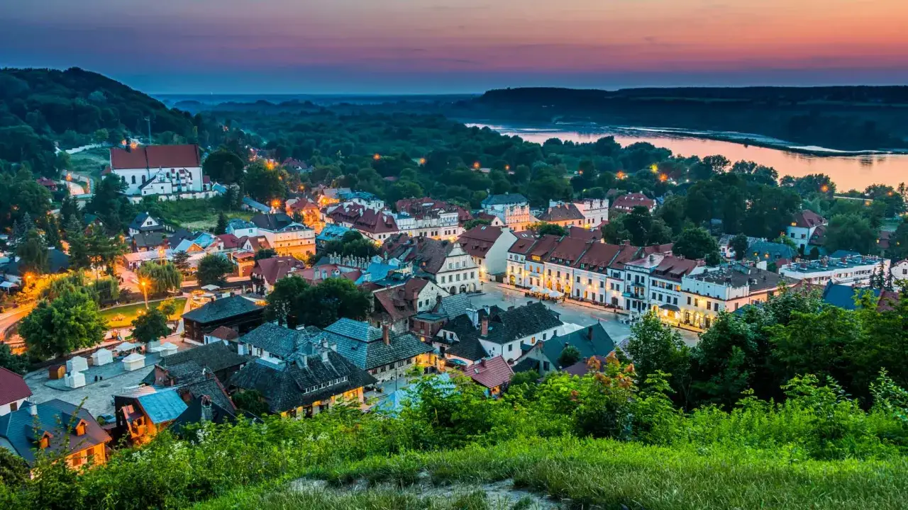 Widok na urokliwy Kazimierz Dolny o zmierzchu. Zabytkowe kamienice, kościół i Wisła tworzą malowniczy krajobraz.